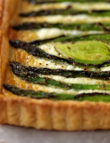 Asparagus Gruyere Tart garnished with herbs on a wooden board