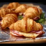 Baked ham and cheese croissants fresh out of the oven, golden and flaky.