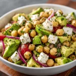 Chickpea Feta Avocado Salad in a colorful bowl garnished with fresh herbs