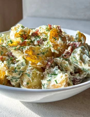 Crispy smashed potato salad served in a bowl with fresh herbs and dressing