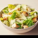 Guiltless high protein Caesar salad bowl with fresh greens and toppings.