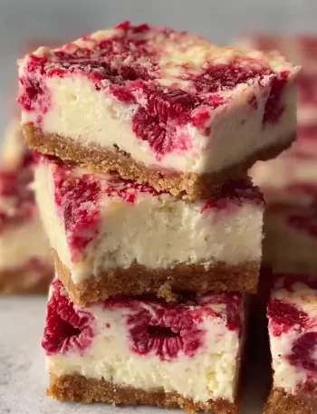 Healthy high protein raspberry cheesecake bars on a plate with fresh raspberries