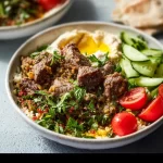 Mediterranean lamb bowls topped with herbs and veggies in a stylish bowl