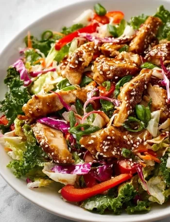 A vibrant sesame chicken salad topped with sesame seeds and fresh vegetables.