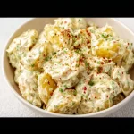 Vegan Potato Salad served in a bowl with fresh herbs and vegetables