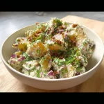 Vegan smashed potato salad served in a bowl with fresh herbs and spices.