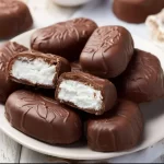 Homemade Bounty Bar chocolate coconut bars on a wooden surface.