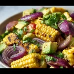 Charred corn avocado salad with roasted red onions served in a bowl