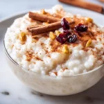 Bowl of creamy classic rice pudding topped with a sprinkle of cinnamon