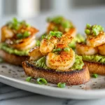 Delicious Garlic Shrimp Crostini topped with Avocado for a delightful appetizer.