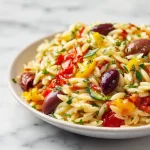 A colorful bowl of Mediterranean Orzo Salad with fresh vegetables and herbs