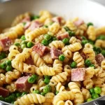 Plate of pasta with peas and ham garnished with parsley