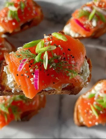 Delicious smoked salmon crostini garnished with herbs and served on a platter