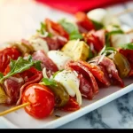 Viral antipasto skewers with salami, mozzarella, and roasted peppers on a platter.