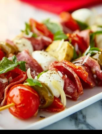 Viral antipasto skewers with salami, mozzarella, and roasted peppers on a platter.