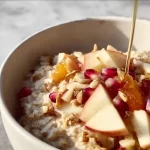 Bowl of warm apple cinnamon oatmeal topped with fresh apples and cinnamon