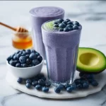 Creamy avocado blueberry smoothie in a glass with fresh fruits