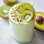 Avocado Kiwi Smoothie in a glass topped with kiwi slices