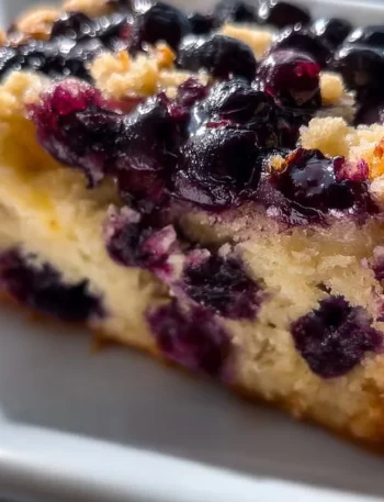 Slice of Blueberry Lemon Loaf with blueberries and lemon zest on a plate