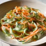 Creamy cucumber and carrot salad in a bowl garnished with herbs