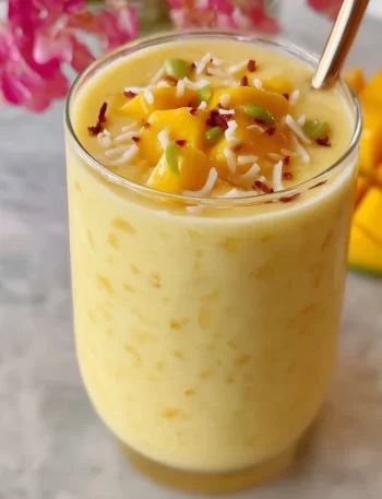 Creamy mango smoothie drink with fresh mango slices on top