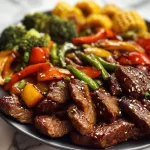 Delicious cowboy stir fry on a Blackstone grill featuring colorful vegetables and beef.
