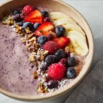 Frozen fruit smoothie bowl topped with fresh berries and granola.