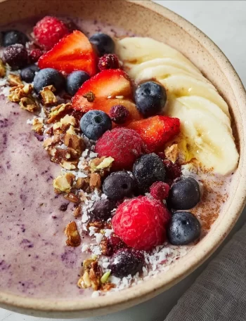 Frozen fruit smoothie bowl topped with fresh berries and granola.