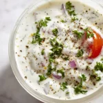 Bowl of homemade Greek yogurt ranch dressing with fresh herbs and vegetables