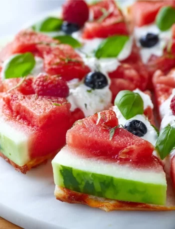 Colorful healthy watermelon fruit pizza topped with yogurt and berries