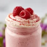 High Protein Raspberry Cheesecake Smoothie in a glass with fresh raspberries on top