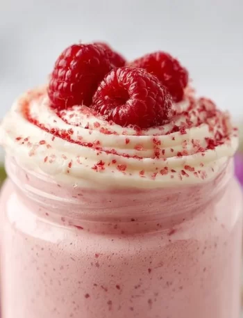 High Protein Raspberry Cheesecake Smoothie in a glass with fresh raspberries on top