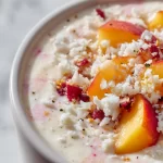 Delicious Peach Coconut Smoothie in a glass with fresh peaches and coconut flakes.