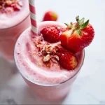 A delicious strawberry smoothie in a glass with fresh strawberries