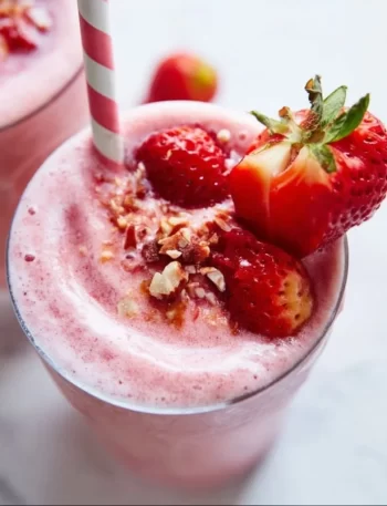 A delicious strawberry smoothie in a glass with fresh strawberries