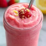 Delicious strawberry lemon smoothie in a glass garnished with fresh strawberries and lemons