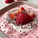 Strawberry milkshake chia pudding topped with fresh strawberries and chia seeds.