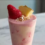 Strawberry Pina Colada smoothie in a glass with fresh strawberries and coconut.