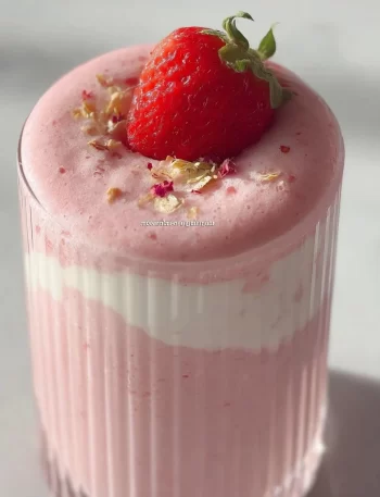 Delicious strawberry yogurt smoothie in a glass topped with fresh strawberries.