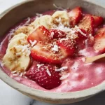 Strawberry banana smoothie bowl topped with fresh fruits and granola