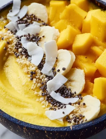 Thick Mango Smoothie Bowl without banana, topped with fruits and granola.