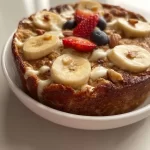 Bowl of Wholesome Banana Bread Baked Oats garnished with banana slices and nuts