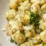 Creamy pesto gnocchi dish served in a bowl, garnished with herbs