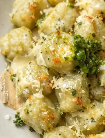 Creamy pesto gnocchi dish served in a bowl, garnished with herbs