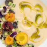 Chilled peach soup served in a bowl, garnished with mint leaves