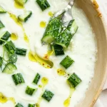 Fresh cucumber gazpacho served in a bowl with herbs and garnishes