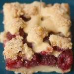 No-bake raspberry crumb bars topped with crumbs, served on a dessert plate.