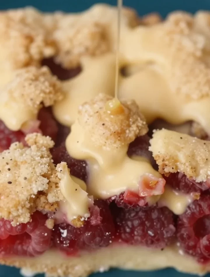 No-bake raspberry crumb bars topped with crumbs, served on a dessert plate.