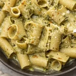 One-pan creamy pesto pasta dish topped with fresh basil and cheese