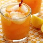 Refreshing Peach Lemonade in a glass with fresh peaches and lemons